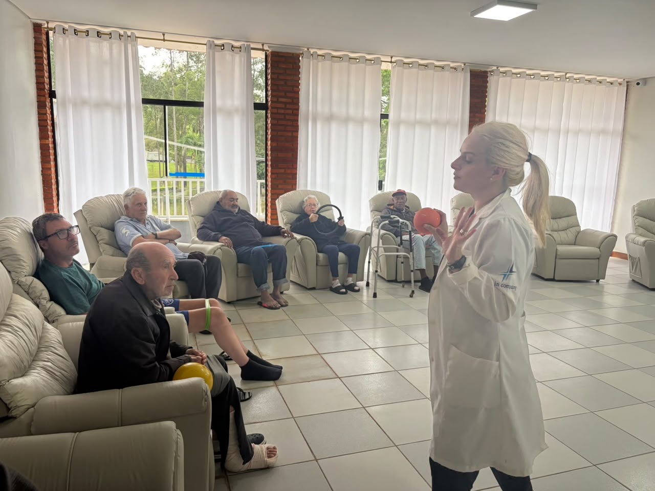 Profissional conduzindo uma atividade com moradores na sala de convivência.